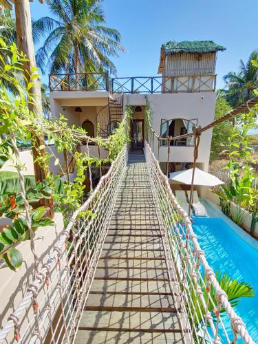 a bridge over a swimming pool in front of a house at Red Sands Mui Ne in Phan Thiet