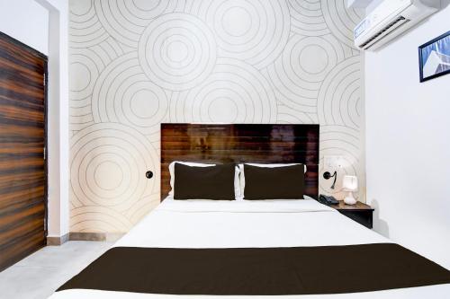 a bedroom with a large white bed and a wall at Super Townhouse Chandrasekharpur in Bhubaneshwar