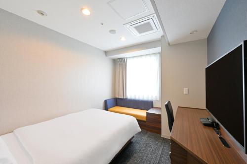 a bedroom with a bed and a desk and a tv at Via Inn Okayama in Okayama