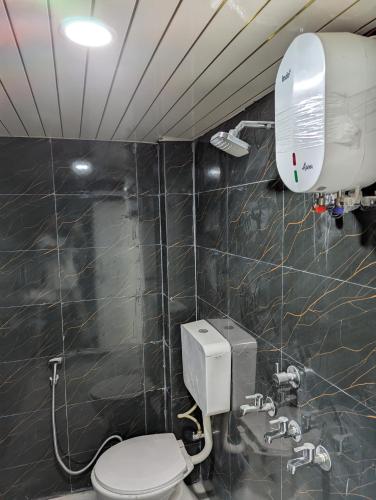 a bathroom with a toilet and a air conditioner at Meenakshi Guest House in Varanasi