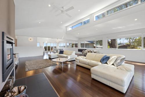 a living room with white furniture and a tv at Eagles Nest - Merrijig - Sleeps 10 in Merrijig