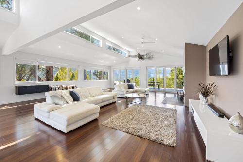 a living room with white furniture and windows at Eagles Nest - Merrijig - Sleeps 10 in Merrijig