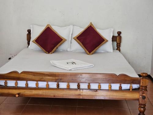 a wooden bed with two pillows on top of it at Cicily Cottage in Munnar