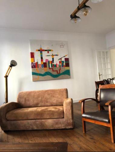 a living room with a couch and a painting on the wall at Les 3 petites pommes in Alençon