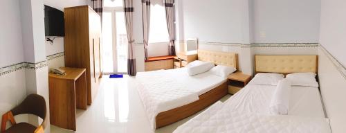 a small room with two beds and a television at Thuỳ Trang Hotel in Ho Chi Minh City