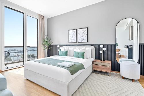 a white bedroom with a large bed and a mirror at Silkhaus Vacation Homes cozy Studio at Al Bandar Marina with gym in Abu Dhabi