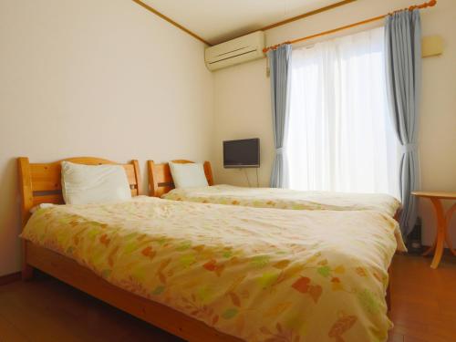 a bedroom with two beds and a window at ペンション花多來 in Shima