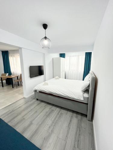 a white bedroom with a bed and a tv at ONE Apartment in Iaşi