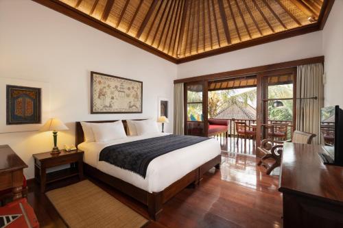 a bedroom with a bed and a table with a desk at Korurua Dijiwa Ubud in Ubud