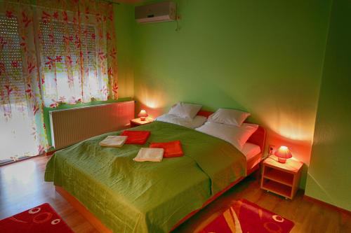 een groene slaapkamer met een groot bed met 2 lampen bij Mars II. Apartman in Szeged