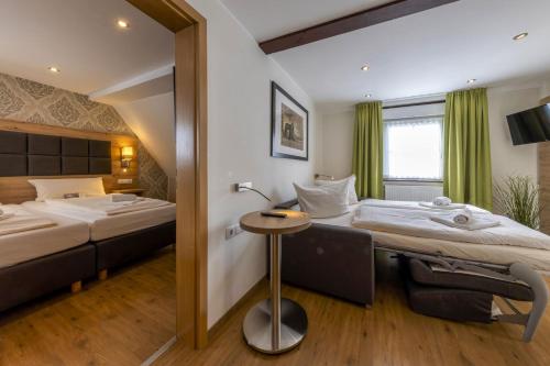 a hotel room with two beds and a table at AKZENT Hotel Restaurant Roter Ochse Rhens bei Koblenz in Rhens