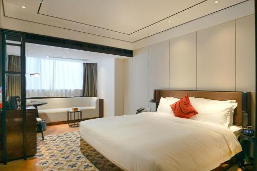 a bedroom with a large white bed with a red pillow at Paco Hotel GuangZhou Zoo Metro Branch Free shuttle bus during the Canton Fair in Guangzhou