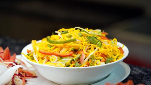 a white bowl filled with noodles and peppers at Yu turn in Greater Noida