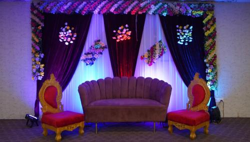 a purple couch and two chairs in front of a stage at Yu turn in Greater Noida