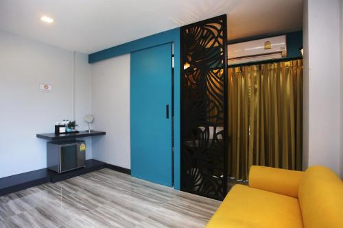 a living room with a yellow couch and a sliding door at Nam Naka Boutique Hotel - SHA Plus in Phuket