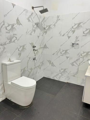 a bathroom with a toilet and a tile wall at Himo Guest Inn in Dehiwala