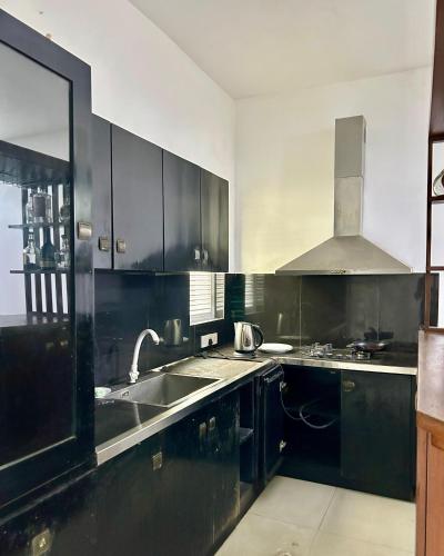 a kitchen with black cabinets and a sink at Himo Guest Inn in Dehiwala