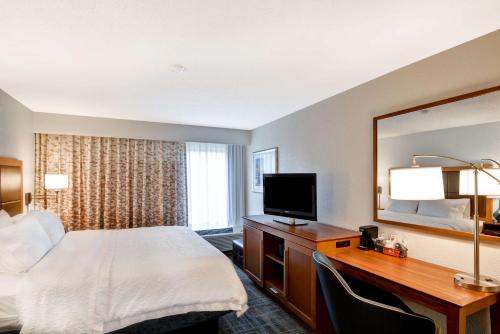 a hotel room with a bed and a desk with a television at Hampton Inn Memphis-Poplar in Memphis