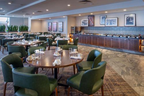 a restaurant with tables and chairs and a bar at Hilton St. Louis Airport in Woodson Terrace