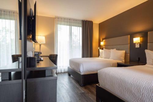 a hotel room with two beds and a television at Ramada by Wyndham Ottawa On The Rideau in Ottawa
