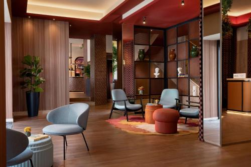 a waiting room with chairs and tables in a lobby at The Spring House Hotel Rome Vatican, Tapestry Collection Hilton in Rome