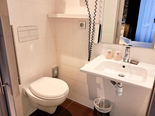 a white bathroom with a toilet and a sink at Hôtel de Paris in Besançon