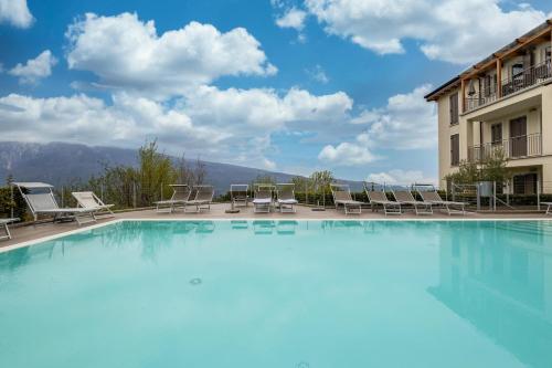 a large swimming pool with chairs and a building at Residence La Villa Diamante in Tignale