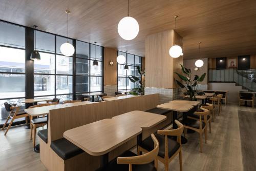 a restaurant with wooden tables and chairs and windows at Kindness Hotel - Jhong Jheng in Kaohsiung