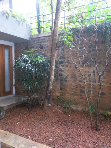 a stone wall with a tree next to a building at Paradise Itzu in Kandy