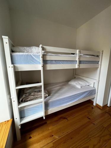 deux lits superposés blancs dans une chambre avec parquet dans l'établissement Le duplex Cornadore, à Saint-Nectaire