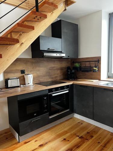 Il comprend une cuisine équipée d'appareils noirs et du parquet. dans l'établissement Le duplex Cornadore, à Saint-Nectaire