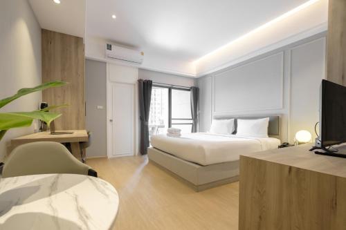 a bedroom with a bed and a desk and a tv at Boss Mansion in Bangkok