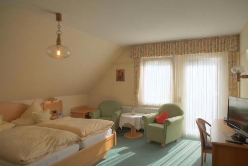 a bedroom with a bed and a tv and chairs at Pension Zueschener Bauernstuben in Winterberg