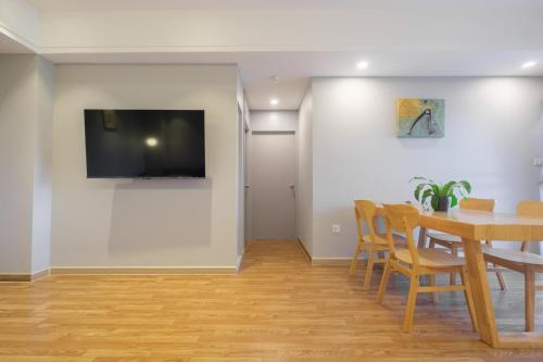 a dining room with a table and a television on a wall at Boss Mansion in Bangkok