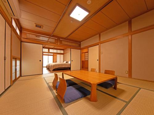 a dining room with a table and a bed at Yufuin Onsen Ryokan Hananomai in Yufuin