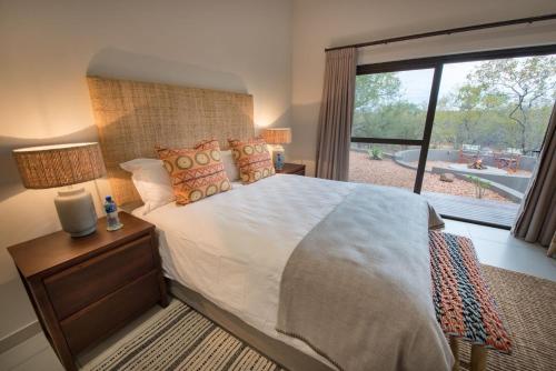 a bedroom with a large bed and a large window at eKhaya Bush Lodge in Hoedspruit