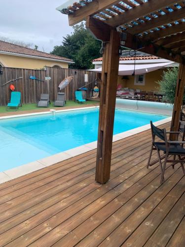 une terrasse en bois avec une piscine et une pergola dans l'établissement Maison piscine, à Carcans
