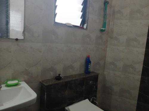 a bathroom with a toilet and a sink and a window at Hotel yogeshwer in Mehsāna