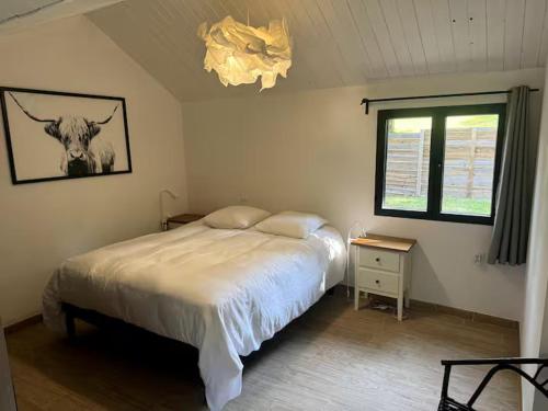 a bedroom with a bed and a picture of a cow at Les lodges de Marie Chalet 3 in Banassac