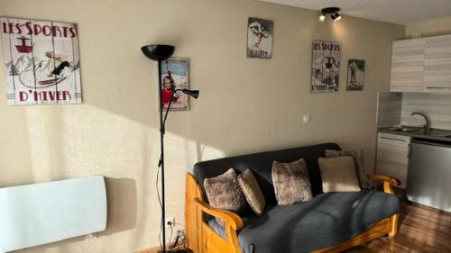 - un salon avec un canapé noir et un microphone dans l'établissement Résidence Chamoisiere - Studio cosy tout confort - Belle vue MAE-0971, à Montgenèvre