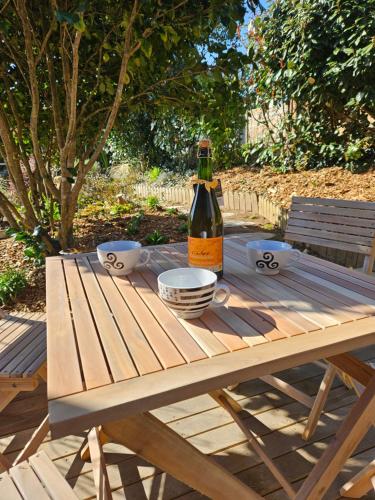a bottle of wine sitting on a wooden picnic table at Gîte Les mouettes qui caquètent in Moëlan-sur-Mer