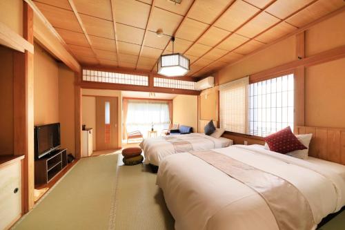 a room with two beds and a flat screen tv at Otogitei Kofu in Achi