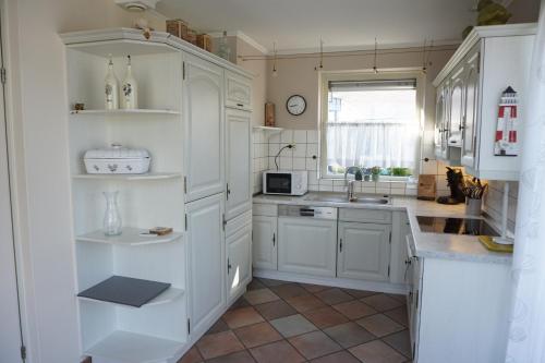 a kitchen with white cabinets and a sink at Kustverhuur, Breskens Zwin 242 in Breskens