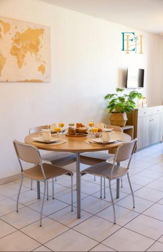 - une table à manger avec 2 chaises et une table avec de la nourriture dans l'établissement Le BOHEME - Séjour en Petite Camargue - 4 personnes, au Grau-du-Roi