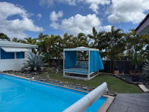 a gazebo by a swimming pool next to a house at Au Bel'vue chez Sandrine "Gite & Chambre d'hôtes" in Le Moule