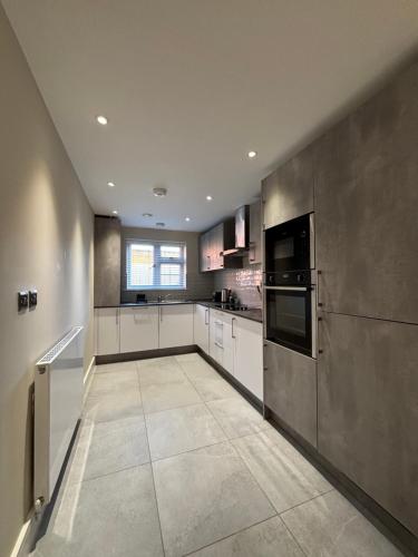 a large kitchen with white cabinets and black appliances at Modern Apartment - BHX NEC - Free Secure Gated Parking in Solihull