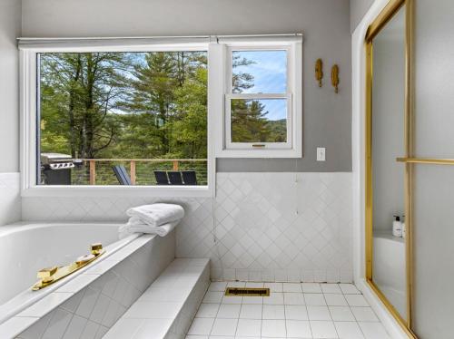 a white bathroom with a tub and a window at Spacious Mountain Retreat set on 7 acres & Pond in Stowe