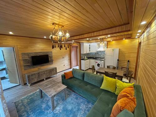 Una sala de estar con un sofá verde y una cocina. en Falay pansiyon, en Uzungöl