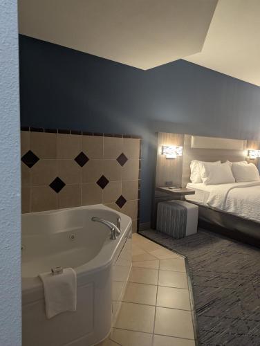 a bathroom with a bath tub and a bed at Holiday Inn Express Hotel & Suites Loveland by IHG in Loveland