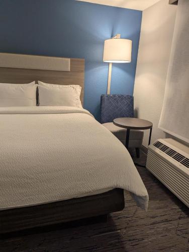 a bedroom with a bed and a table and a lamp at Holiday Inn Express Hotel & Suites Loveland by IHG in Loveland